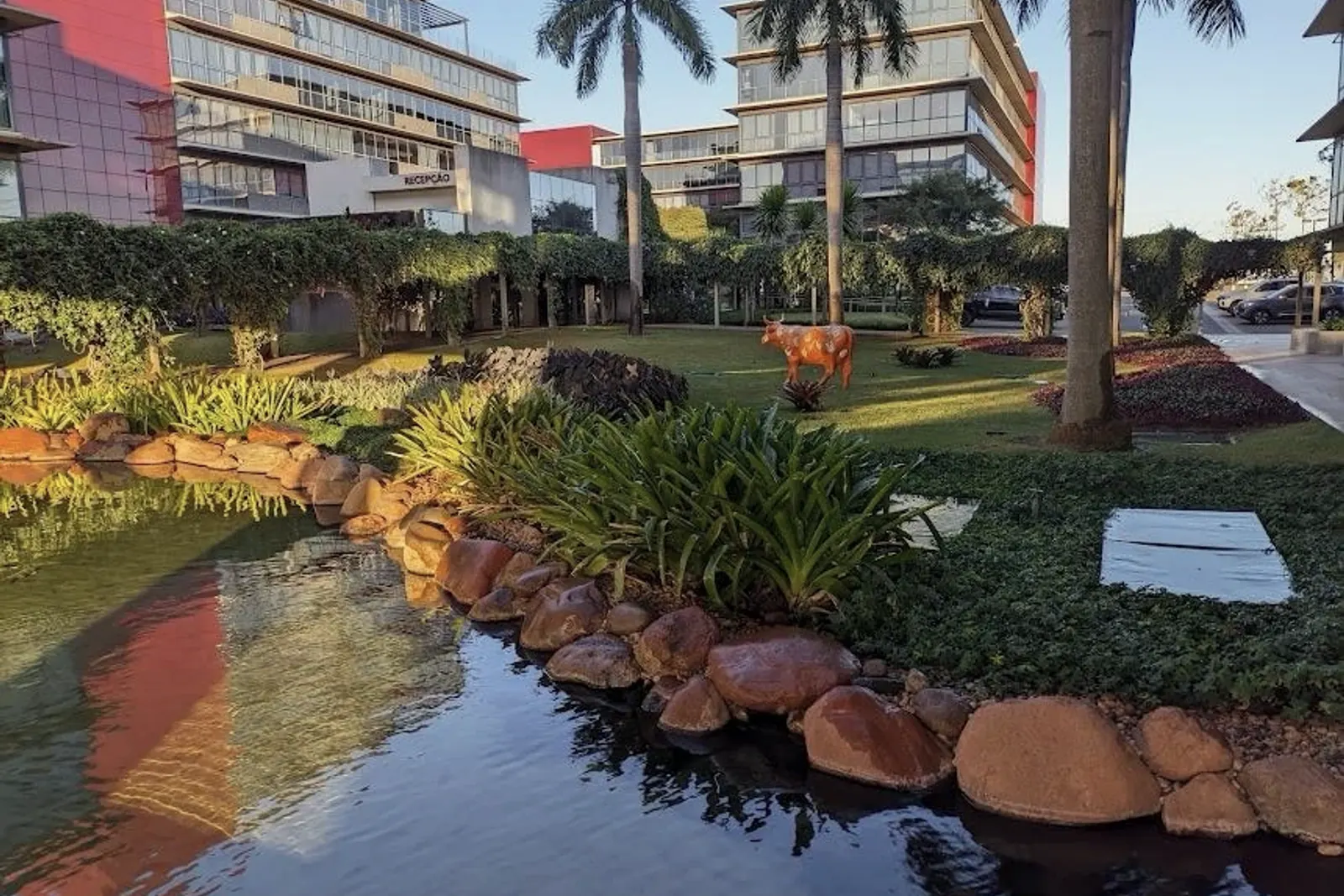 Fachada do prédio onde fica a clínica, com jardim, lago e palmeiras